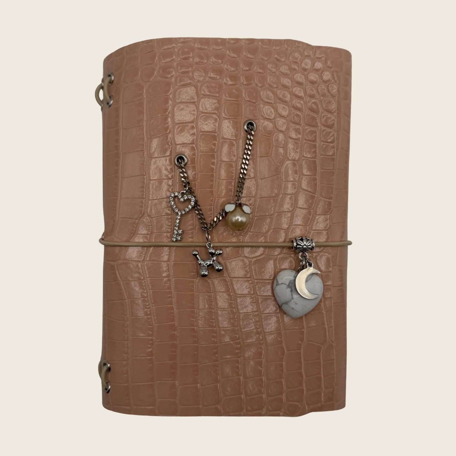Mini Soft blush A6 embossed with a crocodile texture. Finished with silver toned chains and symbolic charms.